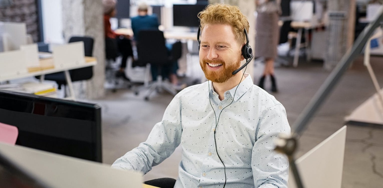 Smiling Man at Desk with Headset